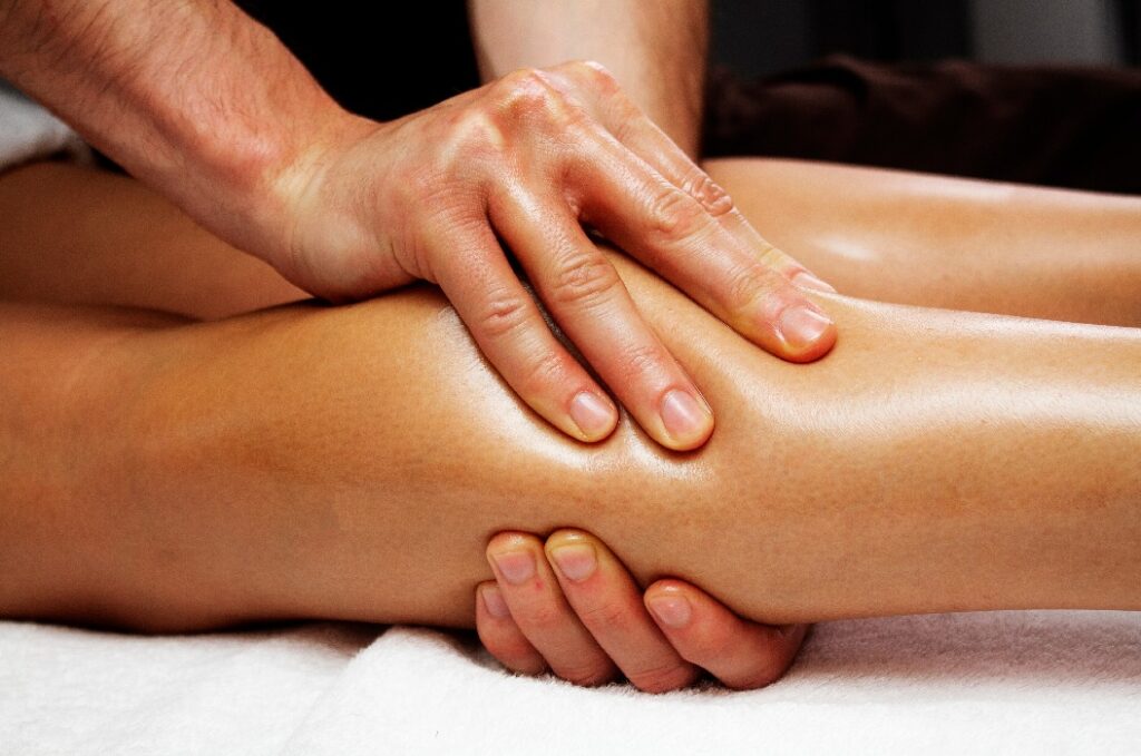 Lymphdrainage-Massage der Beine und Unterschenkel. Weibliche Füße in den Händen eines Masseurs.