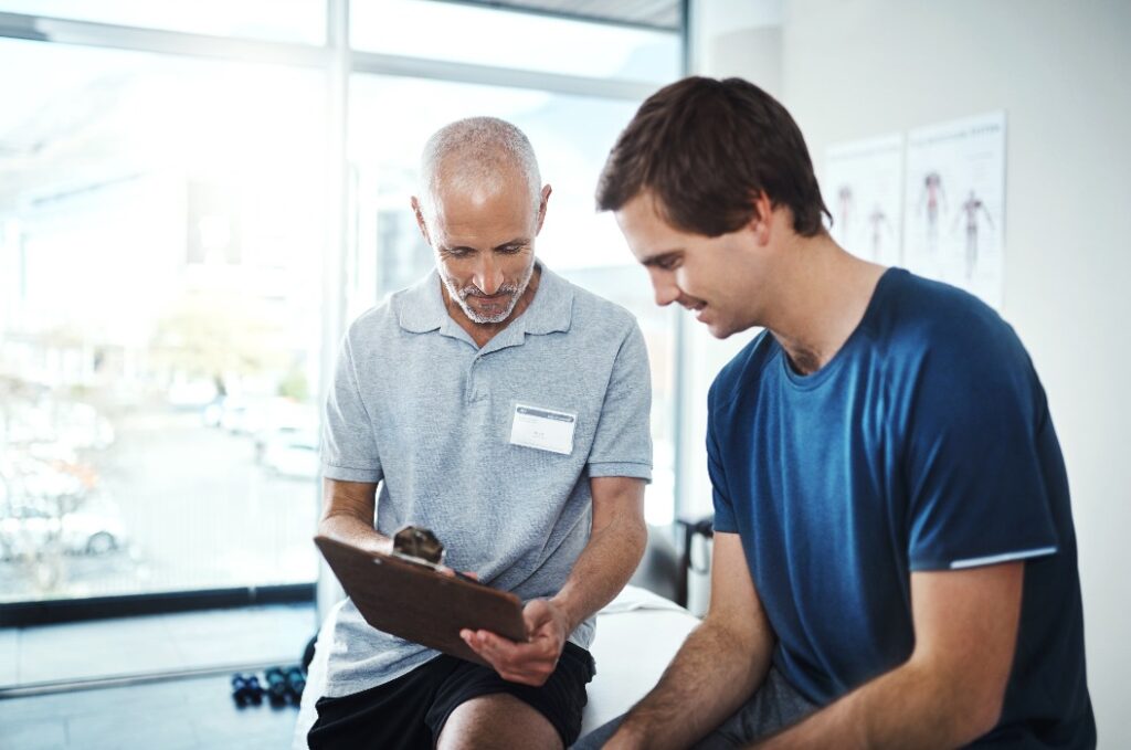 Männer, Physiotherapeuten und glücklich mit Patient für Rehabilitation mit Klemmbrett im Lächeln für Checkliste, Ergebnisse und Bericht. Menschen, und Gesundheitsklinik auf Fitness, Bewegung und Training für Wellness