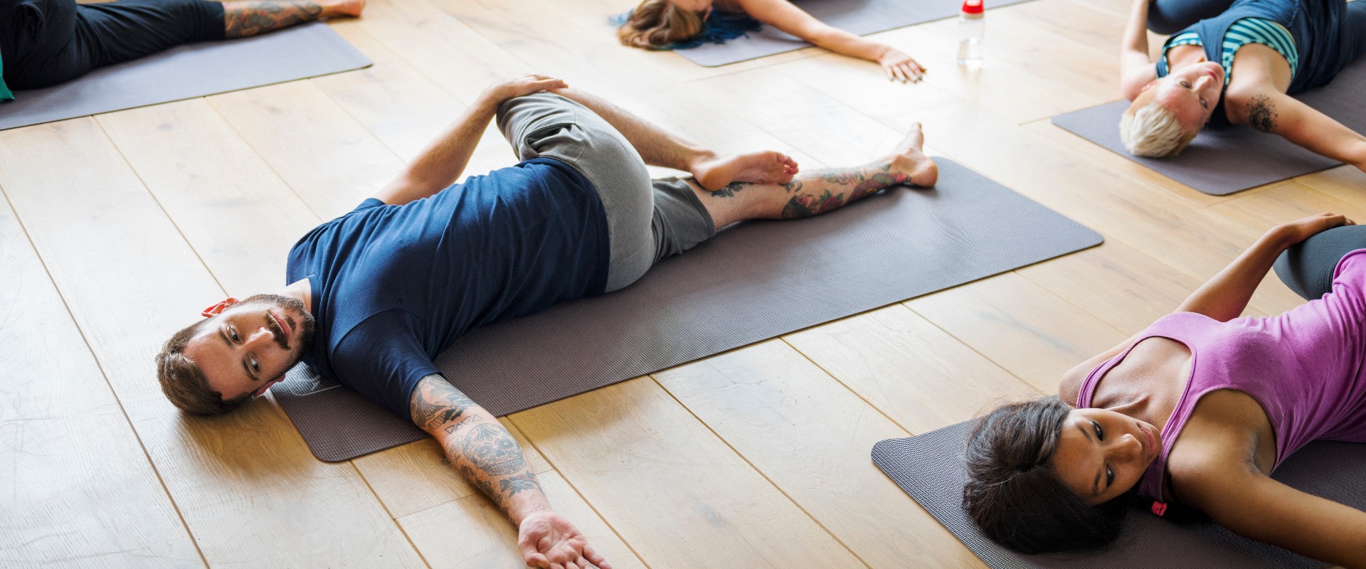 Eine Gruppe unterschiedlicher Personen nimmt an einem Yoga-Kurs teil.
