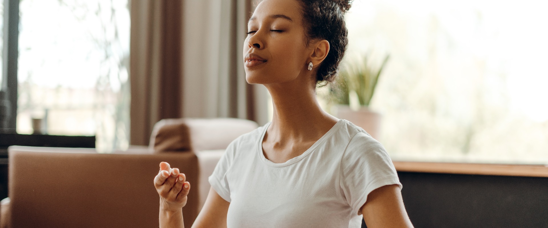 Porträt einer attraktiven afroamerikanischen Frau, die zu Hause Atemmeditation praktiziert