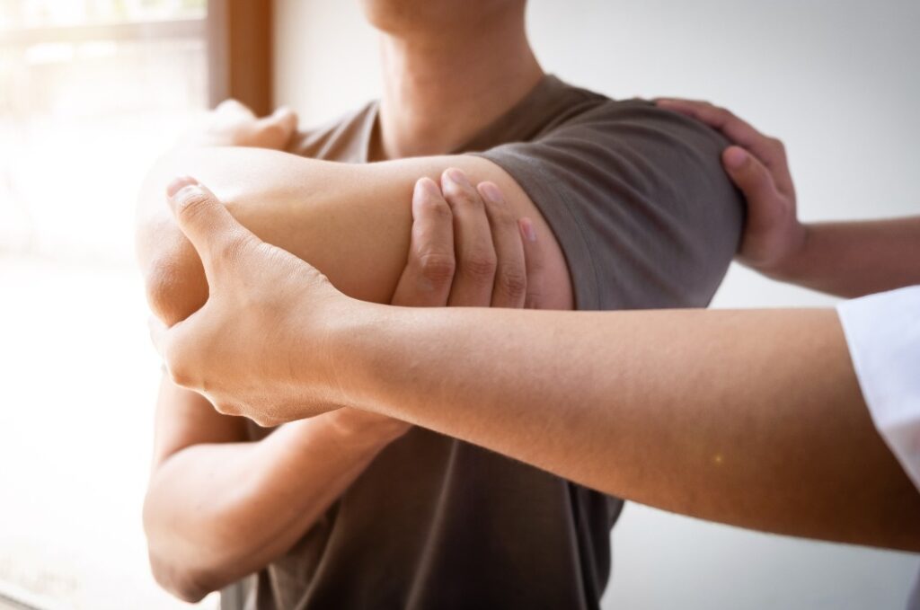 Therapeut, der einen Mann behandelt, der sich eine Verletzung der Rotatorenmanschette zugezogen hat